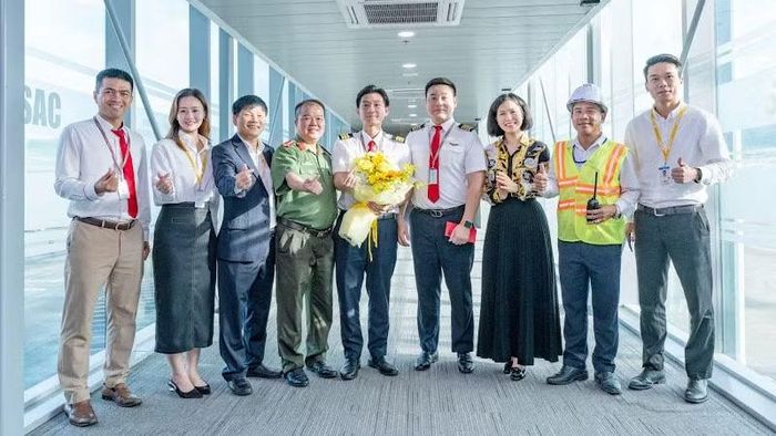 Tổ lái chuyến bay 9G1955 nhận hoa chúc mừng tại ống lồng nối máy bay với nhà ga.(Ảnh: CTV)