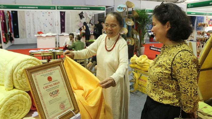 Nghệ nhân Ưu tú Phan Thị Thuận giới thiệu về sản phẩm vải tơ tằm. (Ảnh: MAI ANH)