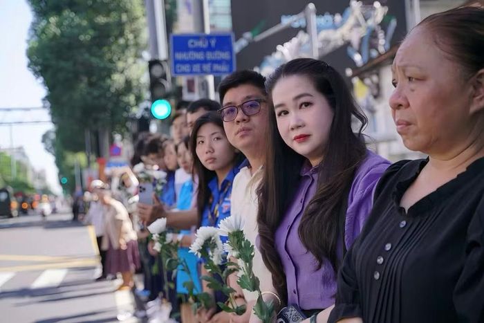  Bà Nguyễn Ngọc Khánh Vân (áo tím) - Hiệu trưởng Trường THPT Marie Curie, cùng giáo viên và học sinh cầm hoa trắng tiễn đoàn di chuyển hài cốt 731 Anh hùng liệt sĩ. 