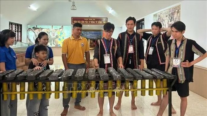 Du khách trải nghiệm đánh đàn đá tại bảo tàng văn hóa dân tộc S'tiêng sóc Bom Bo. Ảnh: Nhật Bình/TTXVN