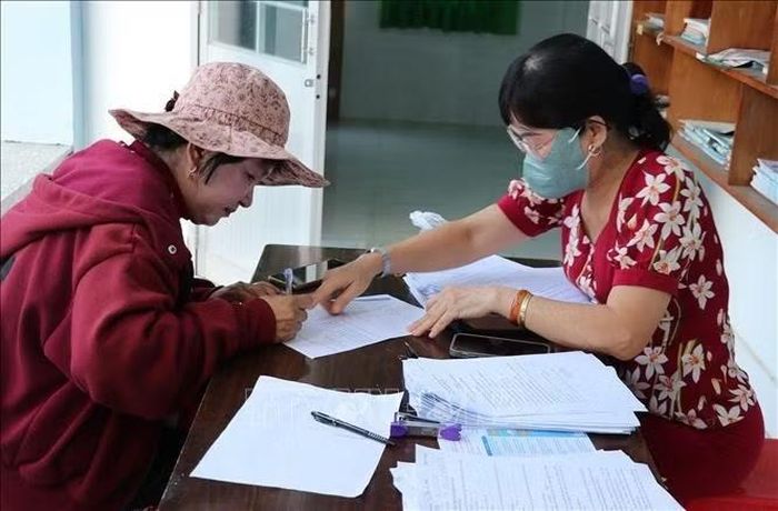 Thành viên “Tổ công nghệ số cộng đồng” ở xã Bình Ninh, tỉnh Đồng Tháp hỗ trợ người dân cập nhật dữ liệu trên VNeID. Ảnh: Hữu Chí/TTXVN