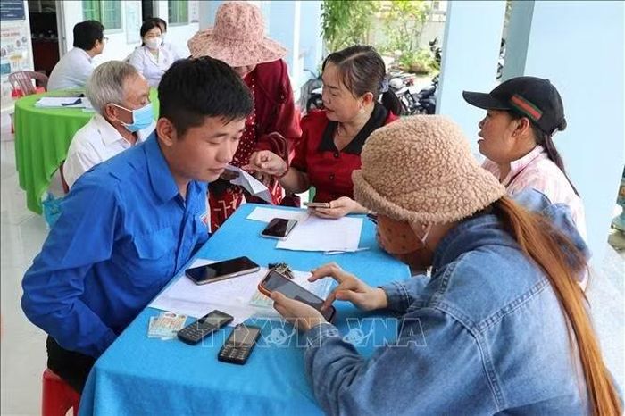 Thành viên “Tổ công nghệ số cộng đồng” ở xã Bình Ninh, tỉnh Đồng Tháp hỗ trợ người dân cập nhật dữ liệu trên VNeID. Ảnh: Hữu Chí/TTXVN