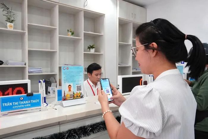  Người dân quét mã đánh giá chất lượng phục vụ của chuyên viên Trung tâm Phục vụ hành chính công phường Bến Thành. Ảnh: THU HƯỜNG 