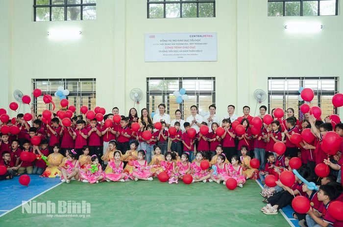 Các đại biểu, thầy cô giáo và học sinh Trường Tiểu học Hà Nam, phân hiệu 2 chụp ảnh lưu niệm tại nhà đa năng mới được bàn giao.