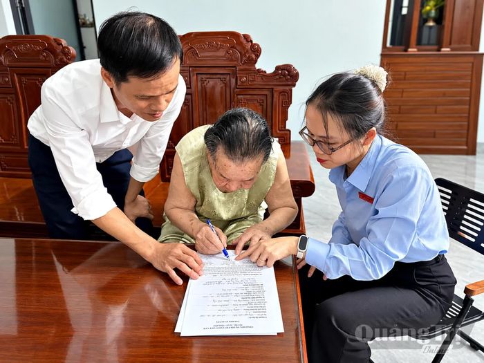 Cán bộ Trung tâm Phục vụ hành chính công xã Nam Hải Lăng hỗ trợ bà Nguyễn Thị Vân, thôn Tây Sơn, thực hiện thủ tục chứng thực văn bản ủy quyền liên quan đến việc nhận lương hưu hằng tháng - Ảnh: L.A