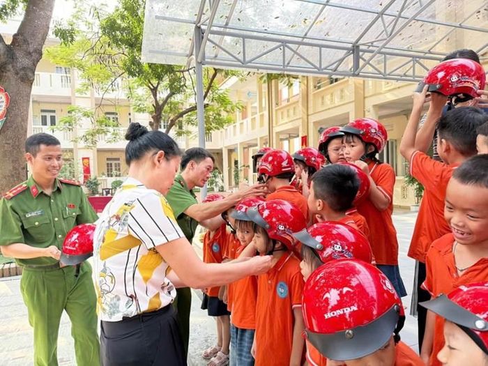 Công an xã Liên Minh tặng mũ bảo hiểm và hướng dẫn học sinh, giáo viên sử dụng bình chữa cháy xách tay.
