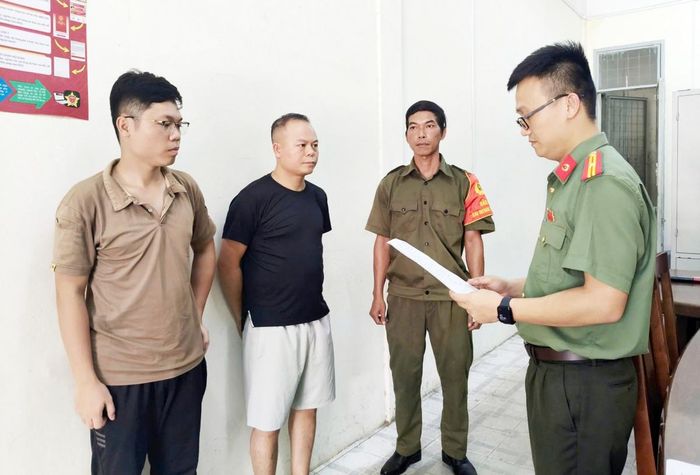 Cơ quan chức năng tống đạt các quyết định đối với Chu Đức Anh (áo đen) và Nguyễn Trung Hiếu (ngoài cùng bên trái) - Ảnh: Công an Đà Nẵng