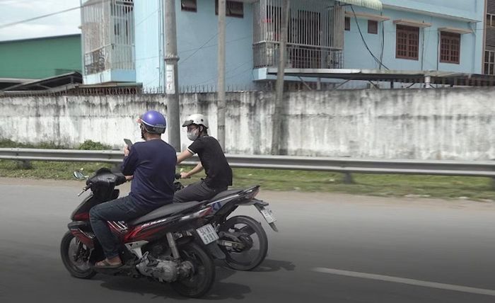 Người đàn ông vừa lái xe mô tô, vừa sử dụng điện thoại trên Quốc lộ 1.