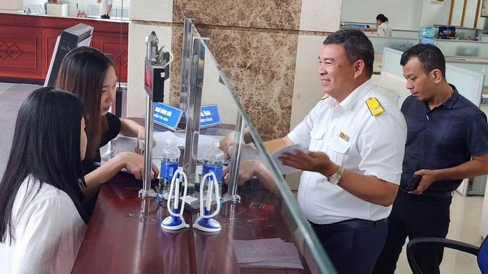 Cán bộ thuế hướng dẫn cho đại diện doanh nghiệp về thủ tục liên quan.