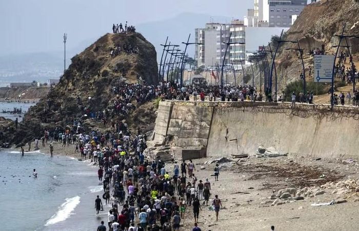 Người di cư trèo qua tuyến đê chắn sóng dọc bờ biển Fnideq (Maroc) vào Ceuta (Tây Ban Nha). Ảnh: AA/TTXVN