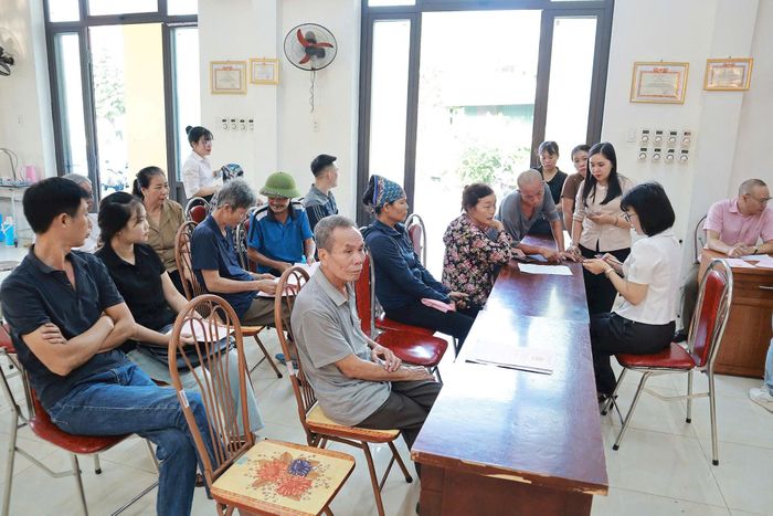 Các hộ dân được cán bộ Ban quản lý dự án Đầu tư - Hạ tầng xã Hát Môn giải đáp băn khoăn liên quan đến phương án bồi thường, hỗ trợ giải phóng mặt bằng. Ảnh: Nguyễn Mai