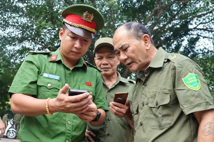 Công an phường hướng dẫn người dự hội nghị quét mã QR khảo sát kiến thức giao thông.