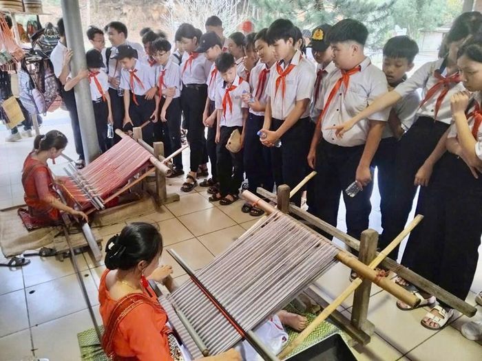 Học sinh quan sát người thực hành dệt thổ cẩm trên khung dệt truyền thống trong hoạt động tìm hiểu nghề tại Mỹ Sơn