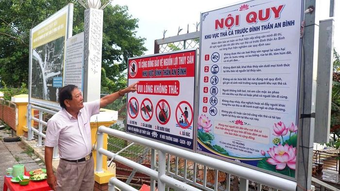 Ông Trương Minh Hải, Trưởng ban Tế tự Đình thần An Bình đứng trước bảng chỉ dẫn nội qui thả cá ở khu bảo tồn