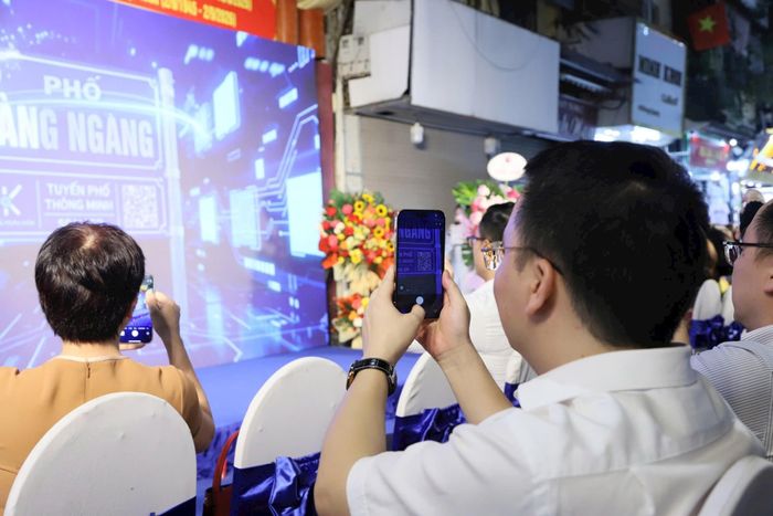 Các đại biểu thực hiện thao tác quét mã - mở ra hành trình khám phá phố cổ trên không gian số tại lễ ra mắt mô hình thí điểm “Tuyến phố thông minh” phường Hoàn Kiếm. Ảnh: BTC
