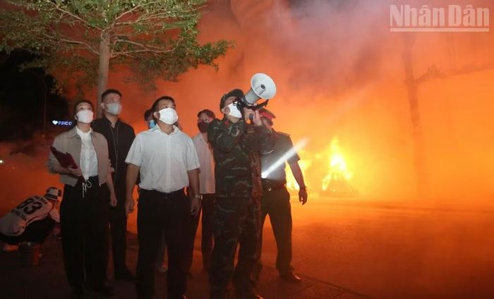 Cán bộ phường Tô Hiệu sử dụng loa cầm tay thông báo tình hình cháy, trấn an và yêu cầu nhân dân sơ tán, di dời tài sản. (Ảnh: QUỐC TUẤN)