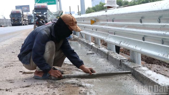 Công nhân thi công những công đoạn cuối phần lan can, lề đường dự án mở rộng cao tốc Thành phố Hồ Chí Minh-Long Thành. (Ảnh: THIÊN VƯƠNG)