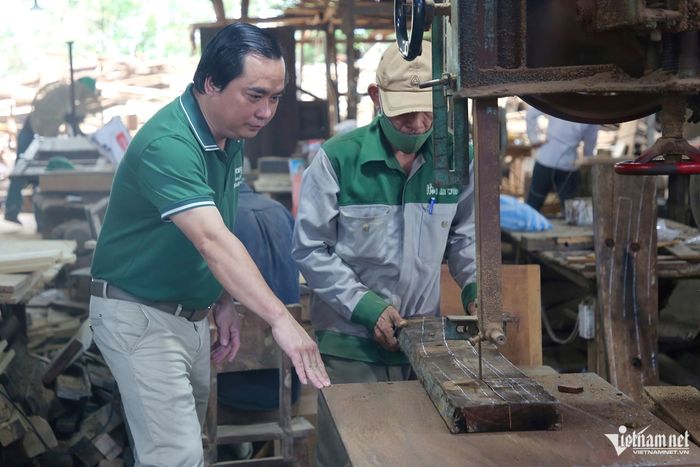 Ông Lê Huỳnh Huyên, chủ Hội An Wood, hướng dẫn thợ xử lý một tấm gỗ thu hồi từ tàu cũ.