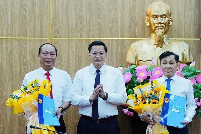 Chủ tịch UBND tỉnh Quảng Ngãi Nguyễn Đức Tâm trao quyết định và tặng hoa chúc mừng ông Nguyễn Quốc Việt (trái) và ông Trần Hoài Thu (phải). Ảnh: N.X