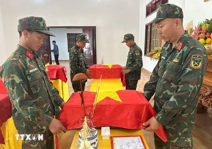 Thành viên Ban Chỉ đạo tìm kiếm, quy tập và xác định danh tính hài cốt liệt sỹ tỉnh Điện Biên thực hiện nghi thức phủ Quốc kỳ lên tiểu sành đựng hài cốt liệt sỹ. (Ảnh: TTXVN phát)