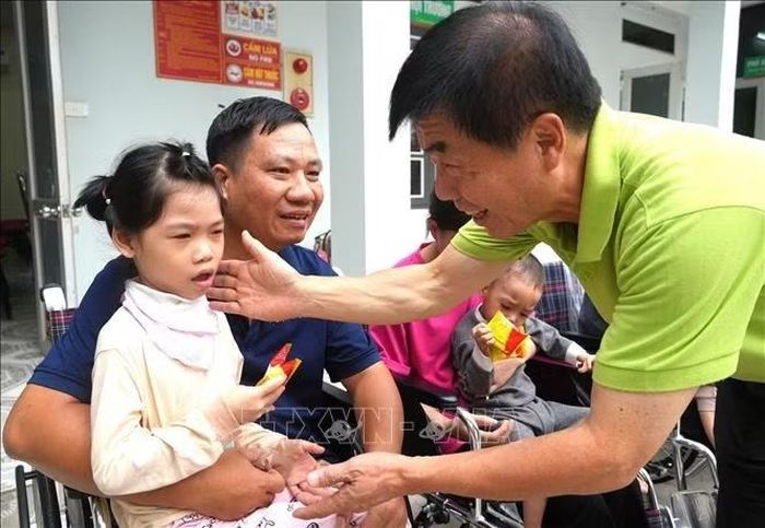 Đại diện Tổ chức Global Friend (Hàn Quốc) ân cần thăm hỏi, động viên cháu nhỏ được nhận xe lăn.