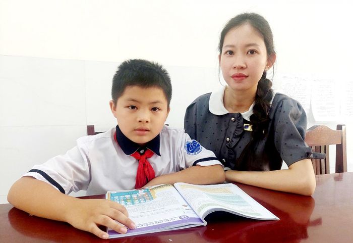 Giáo viên chủ nhiệm hướng dẫn em Tín làm bài.