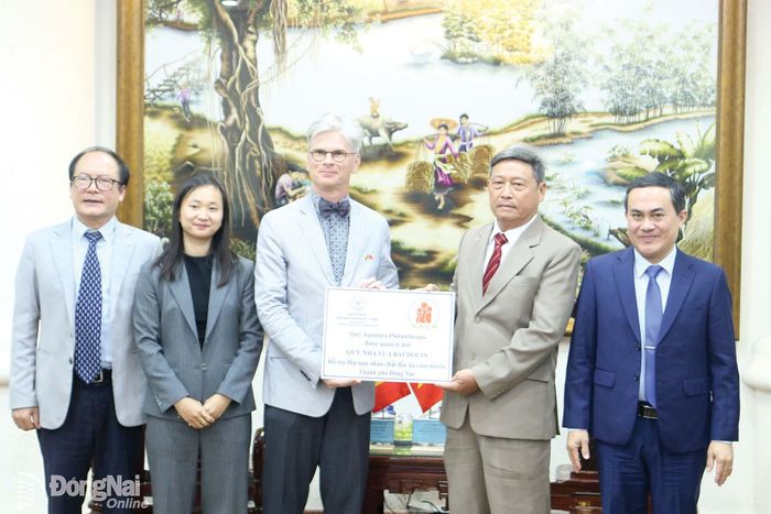 Chủ tịch Hội Nạn nhân chất độc da cam/dioxin thành phố Đồng Nai Mai Văn Nhỏ nhận bảng biểu trưng ủng hộ 20 triệu đồng từ Đại sứ Đặc mệnh toàn quyền Vương quốc Bỉ tại Việt Nam Pieter Leenknegt. Ảnh: Hải Quân