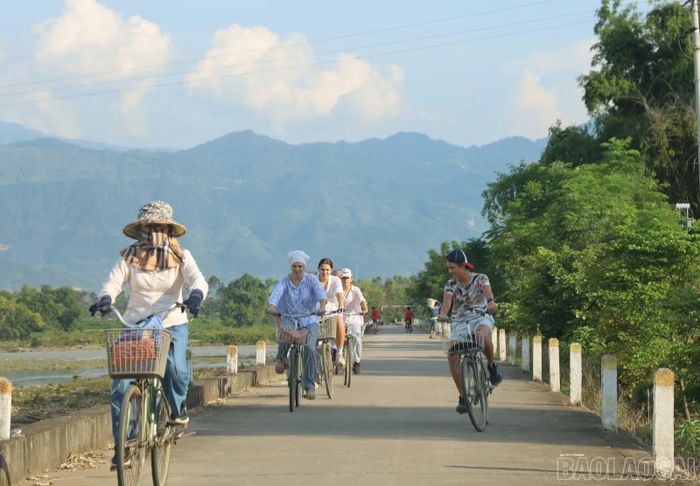 Du khách trải nghiệm đạp xe tham quan bản làng.