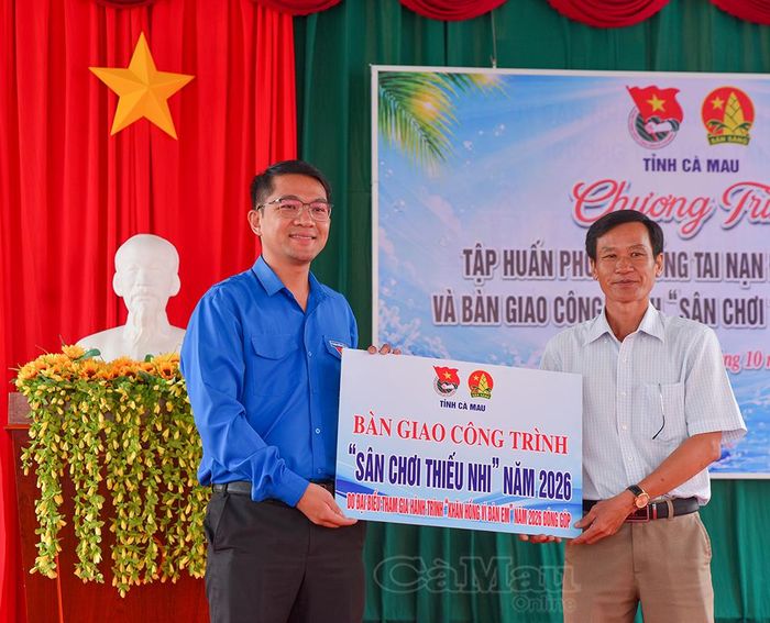 Anh Trần Đăng Khoa, Phó Bí thư Thường trực Tỉnh đoàn Cà Mau (bên trái), trao bảng tượng trưng công trình sân chơi cho ông Tạ Chí Thẩm, Hiệu trưởng Trường Tiểu học Tân Hùng.