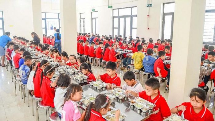 Học sinh ngồi ngay ngắn trong bữa ăn tại nhà ăn bán trú của trường.