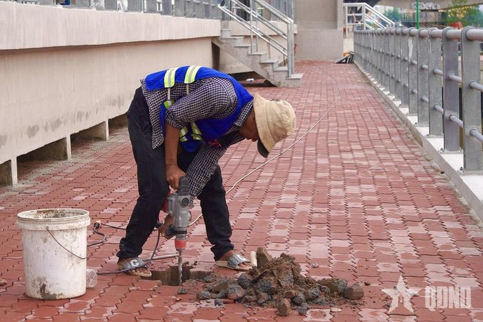 Công nhân xử lý bề mặt gạch lát tại khu vực vỉa hè nội bộ cống Tân Thuận. 