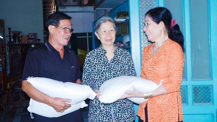 Bà Nguyễn Thị Ngọc Mai (bìa phải), Chi hội trưởng Chi hội phụ nữ ấp 5, xã Tân Nhựt, TPHCM trao tặng gạo đến người có hoàn cảnh khó khăn. Ảnh: NGỌC TRĂM