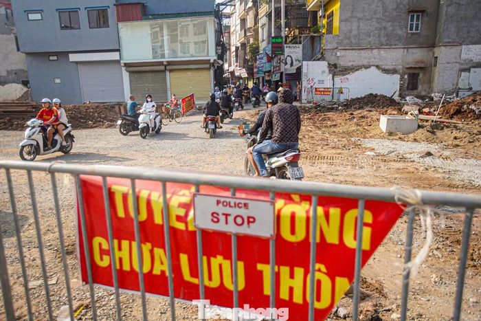 Người đi xe máy phải vượt qua mặt đường gồ ghề, nhiều đất đá và vật liệu xây dựng tại khu vực giao với phố Khương Trung.