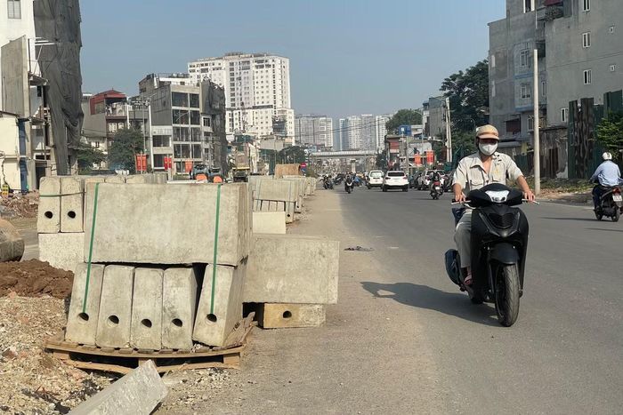 Các cấu kiện bê tông và vật liệu xây dựng được tập kết sát phần đường đang có phương tiện lưu thông.