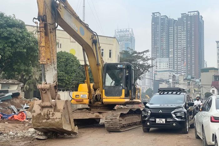 Dòng xe len qua máy xúc đang hoạt động trên công trường.