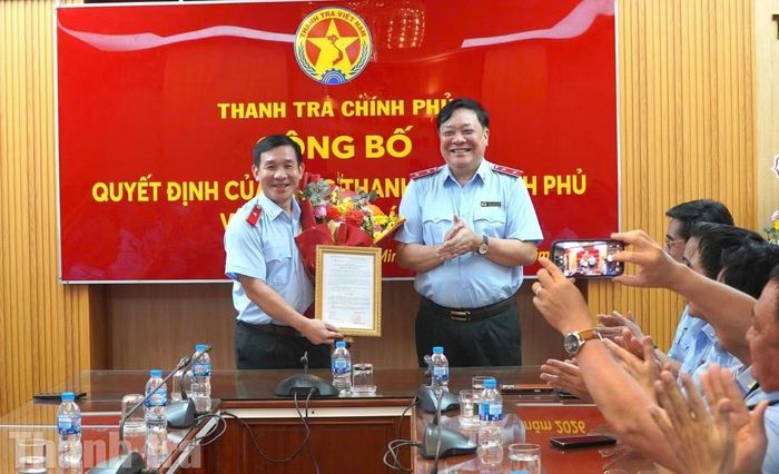 Phó Tổng Thanh tra Chính phủ Phạm Thành Ngại trao quyết định và tặng hoa cho ông Trần Đình Hưng. Ảnh: Báo Thanh tra.