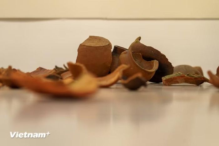 Cận cảnh những mảnh gốm cổ rải trên mặt sàn trong sắp đặt “Những mảnh rời”, hành trình gom nhặt, chắp nối những ký ức văn hóa Chăm qua biến thiên lịch sử. (Ảnh: Thanh Phong/Vietnam+)