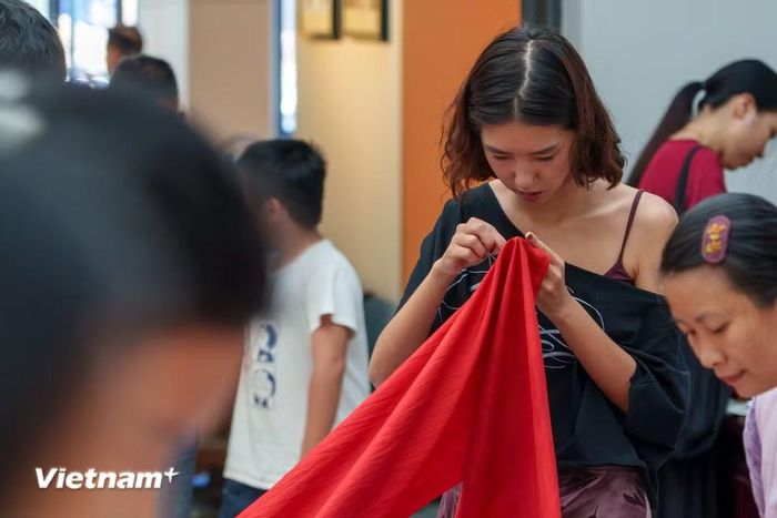 Du khách hào hứng trải nghiệm thao tác khâu và cảm nhận chất liệu tơ lụa tự nhiên tại workshop nghệ thuật cộng đồng “Hương lụa Đồng Dương”. (Ảnh: Thanh Phong/Vietnam+)