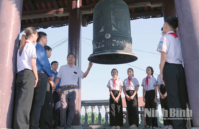 Các em học sinh tìm hiểu về lịch sử di tích tại khu vực tháp chuông Đền Bảo Ninh. Ảnh: Viết Dư