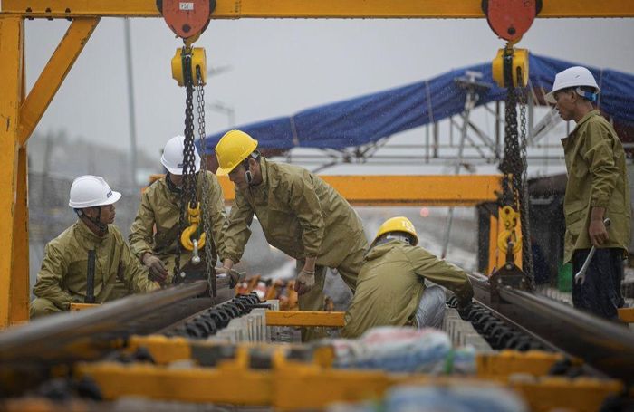 Công nhân đội mưa gấp rút thi công tuyến đường tàu điện LRT.