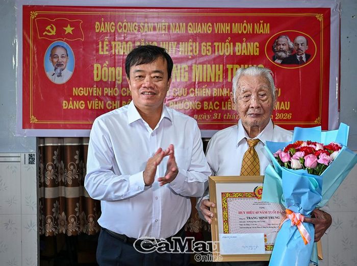 Phó Bí thư Tỉnh uỷ Huỳnh Quốc Việt tặng hoa chúc mừng đồng chí Trang Minh Trung vinh dự nhận Huy hiệu 65 năm tuổi Đảng.