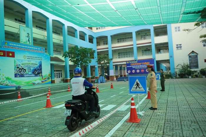 Kỹ thuật viên lái xe an toàn dừng xe, nhường đường cho người đi bộ qua đường tại nơi có biển báo và vạch kẻ đường 