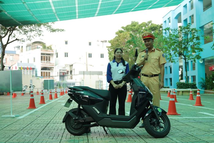 Tuyên truyền viên Đội CSGT Bàn Cờ phối hợp cùng kỹ thuật viên Honda Việt Nam trực tiếp giới thiệu, hướng dẫn học sinh những kiến thức cơ bản về cấu tạo, nguyên lý vận hành xe điện và các thao tác kiểm tra phương tiện trước khi khởi hành 